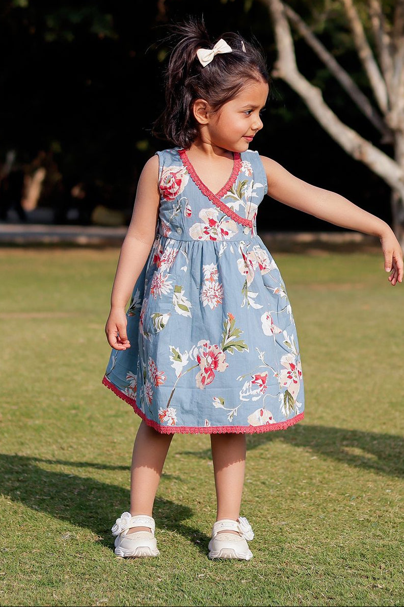 Young girl in a floral dress standing on grass with trees in the background