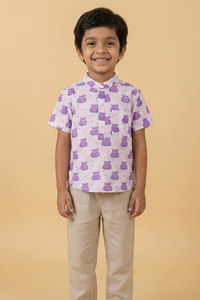 Child wearing a patterned shirt and beige pants on a beige background