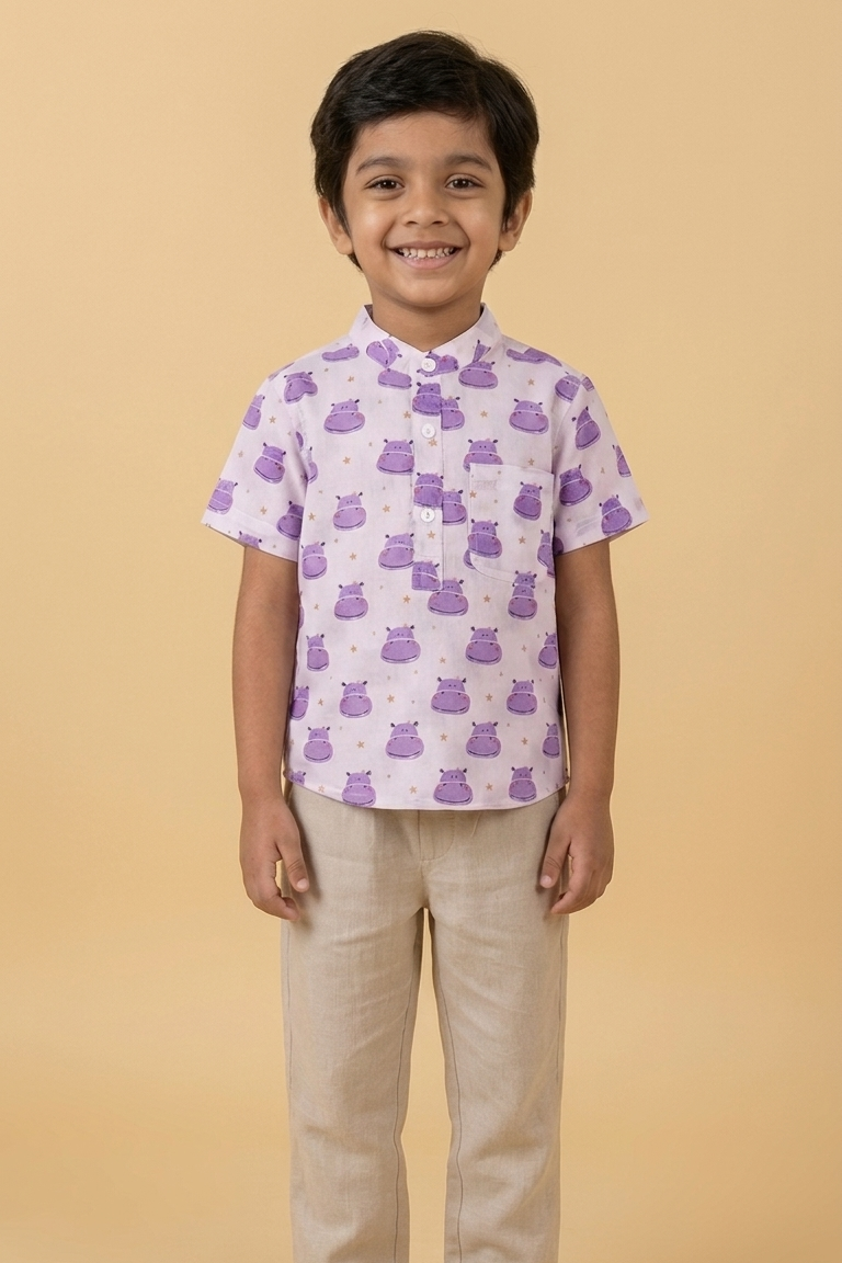 Child wearing a patterned shirt and beige pants on a beige background