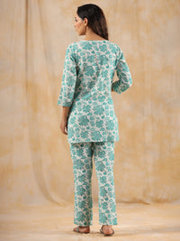 Woman wearing a teal floral outfit against a beige background