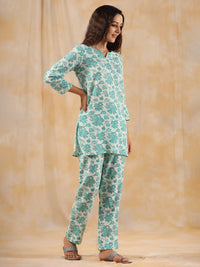 Woman wearing a green floral outfit against a beige background