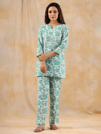 Woman wearing a teal and white floral outfit on a beige background