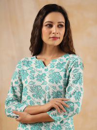 Woman wearing a teal floral patterned top against a beige background
