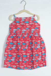 red dress with blue fish pattern on a hanger against a white background