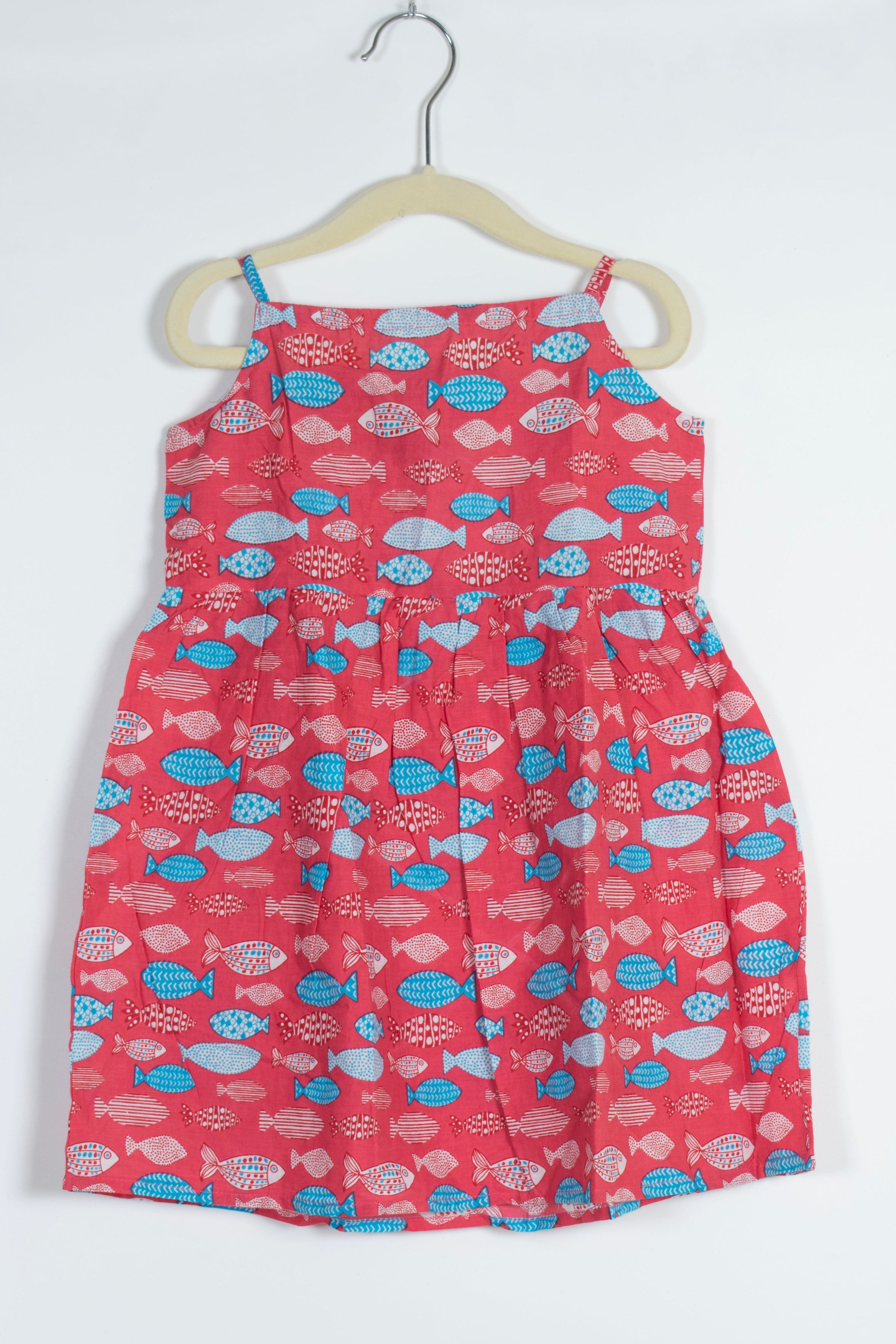 red dress with blue fish pattern on a hanger against a white background