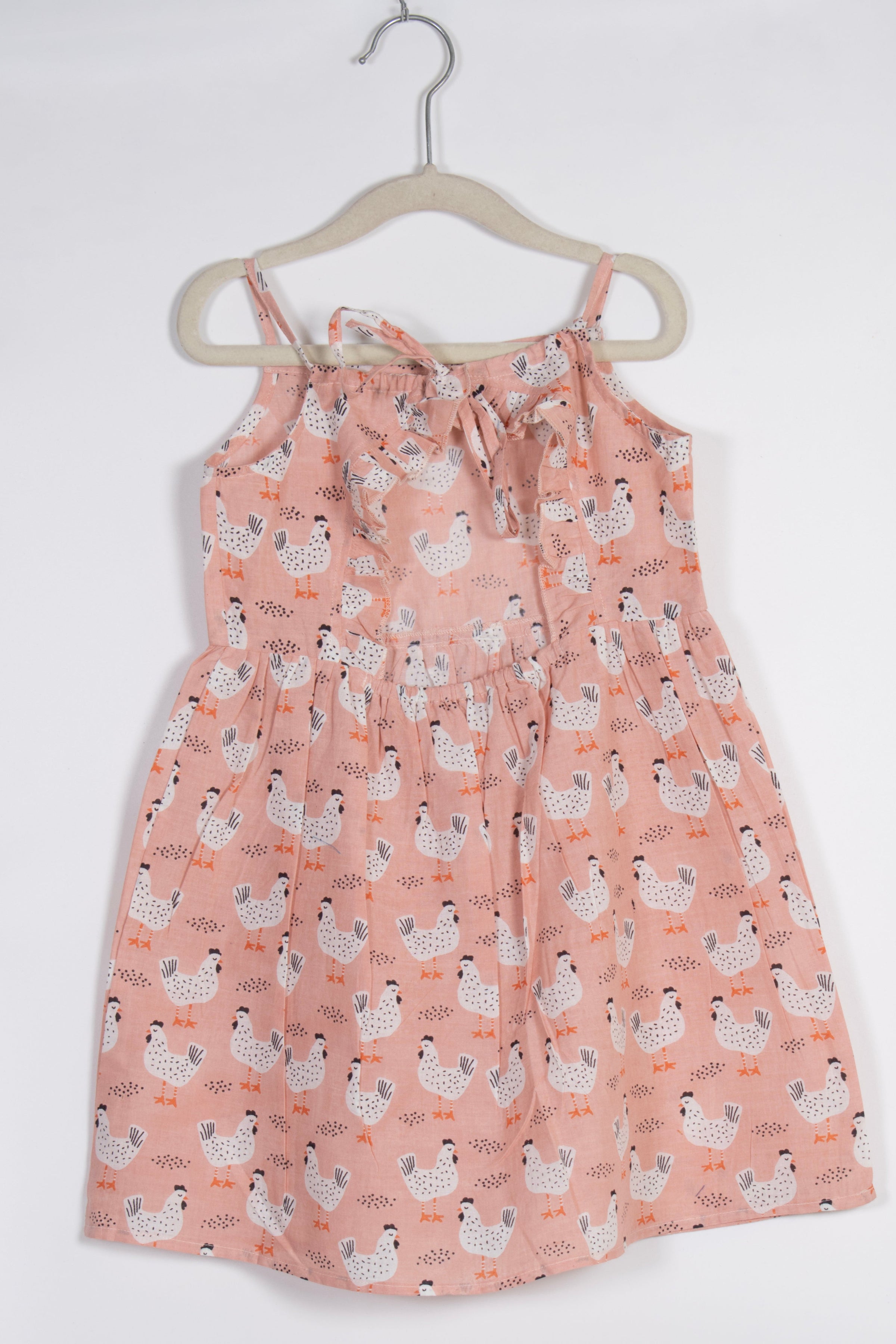 peach dress with chicken pattern on a hanger against a white background