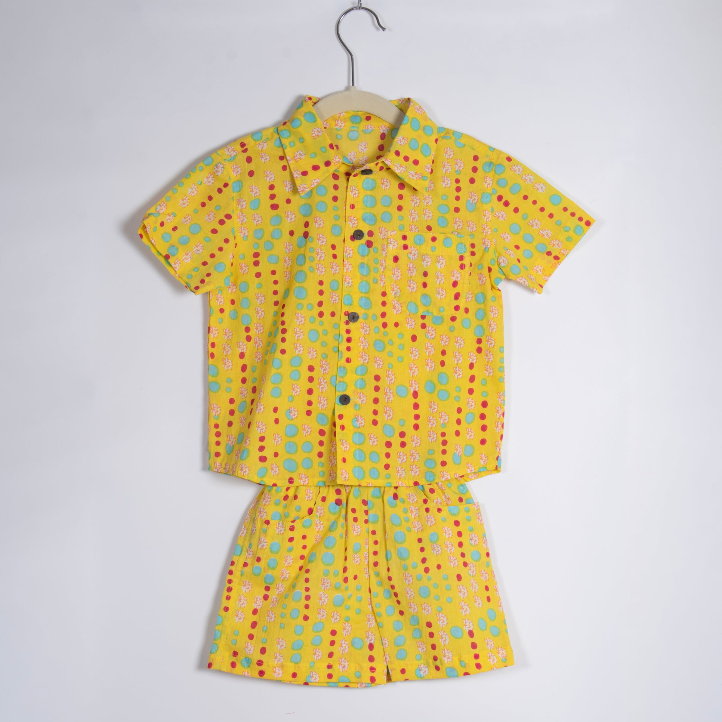 Yellow children's outfit with colorful polka dot pattern on a white background