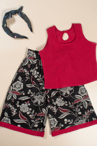 Red tank top and black floral culotte with a headband on a beige background