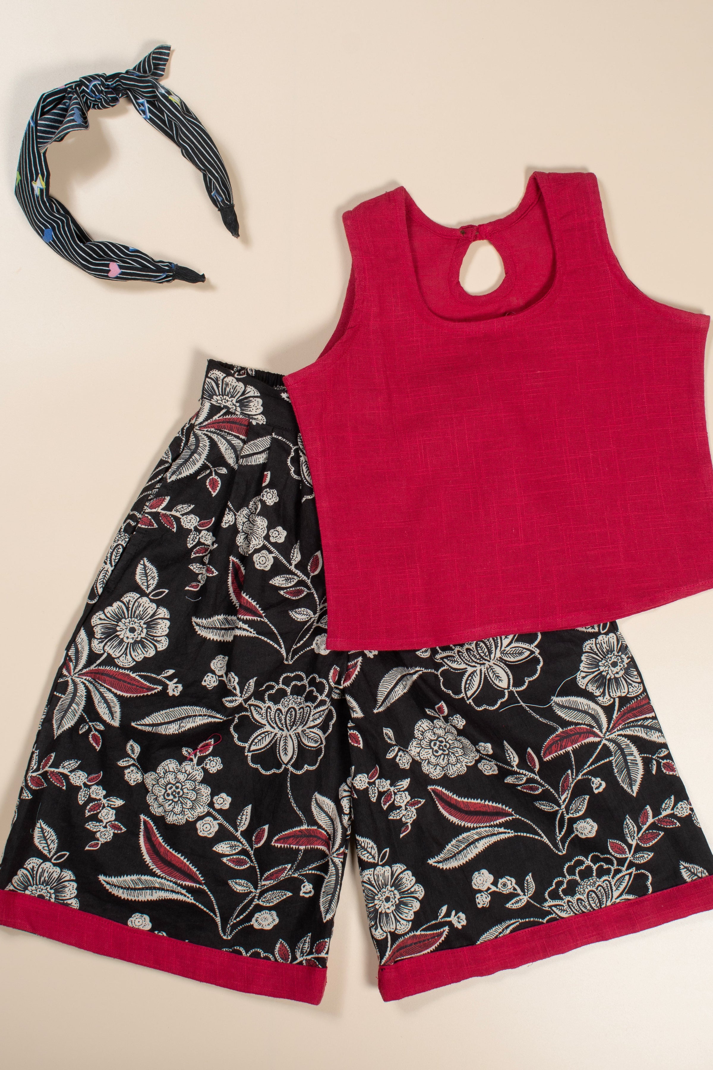 Red tank top and black floral culotte with a headband on a beige background