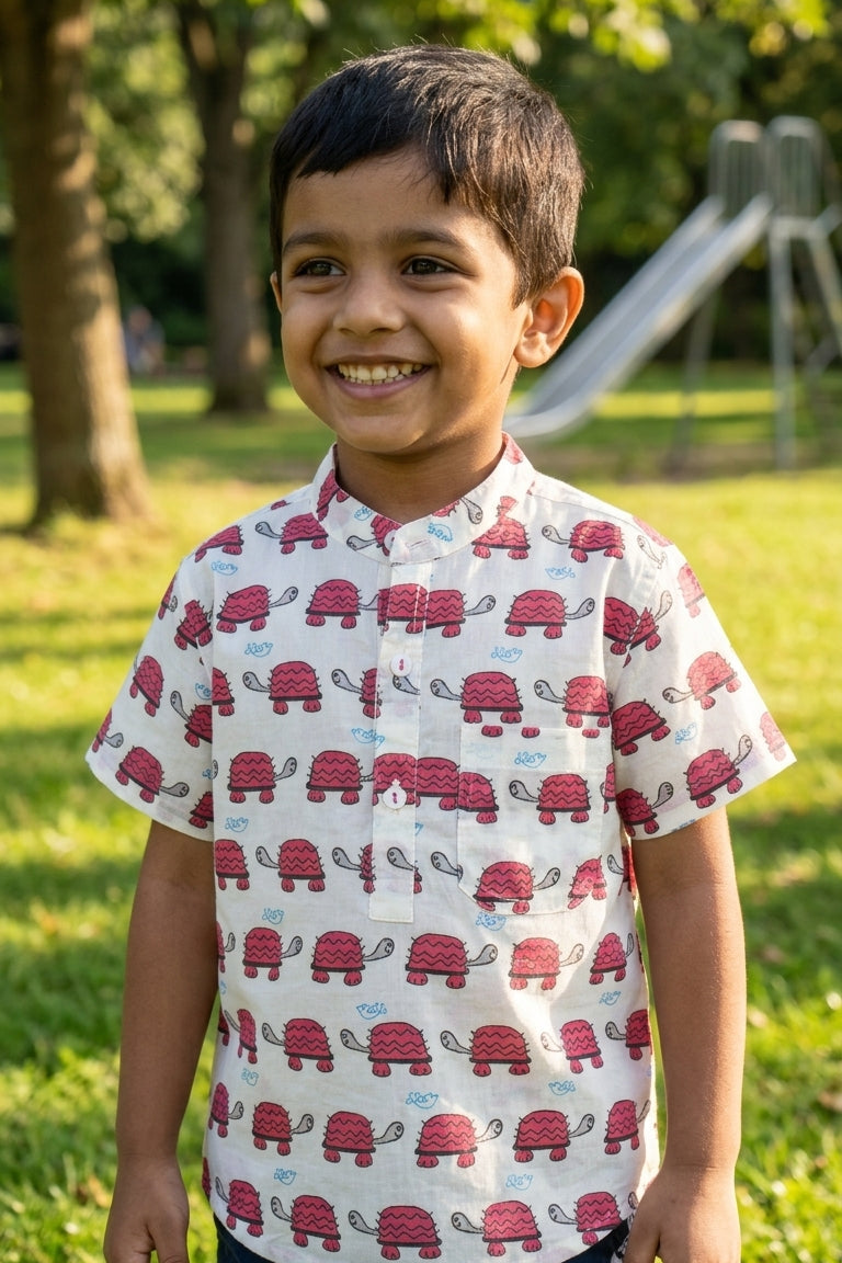 Child wearing a shirt with red turtle pattern in a park