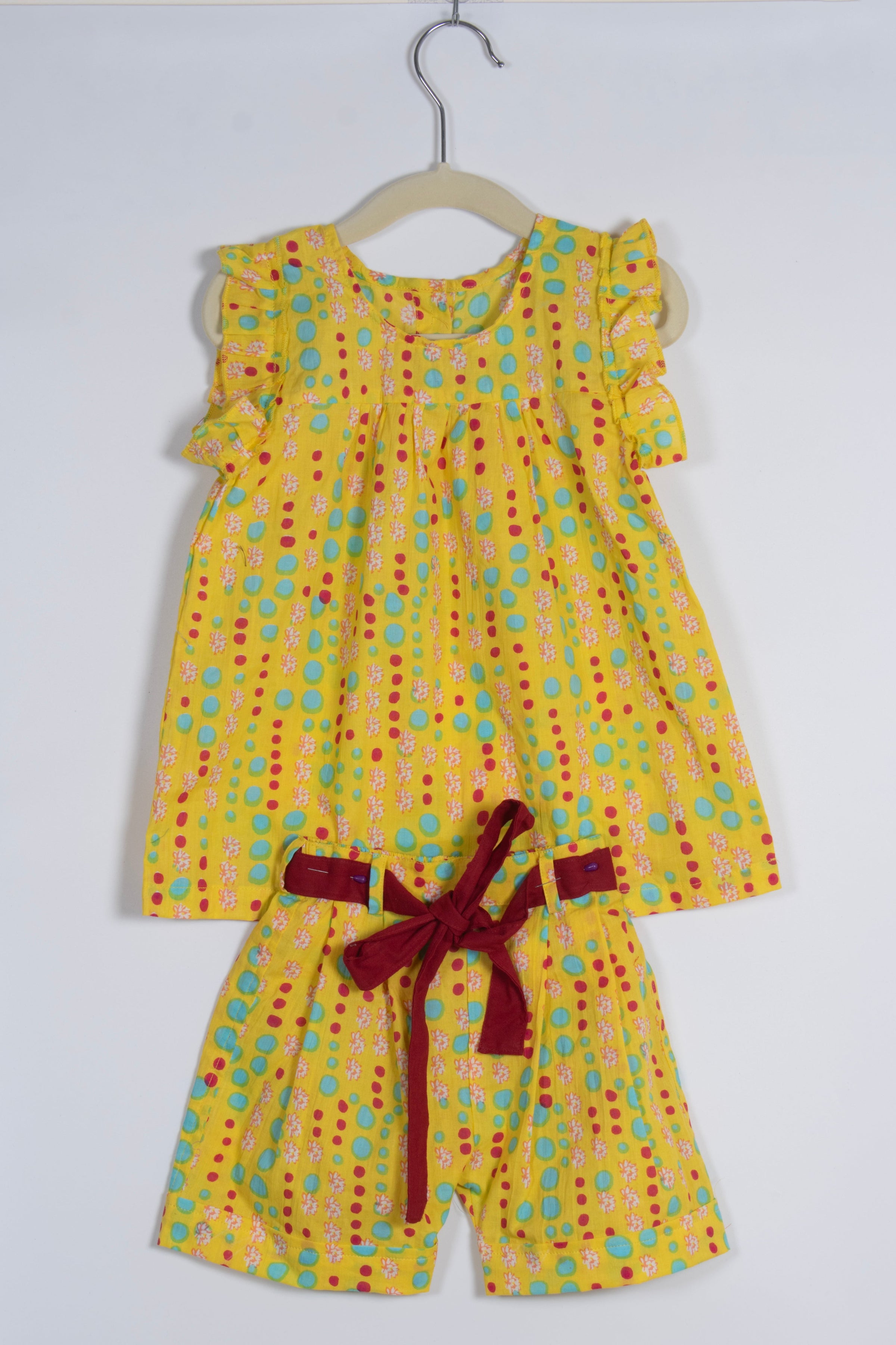 Yellow polka dot dress with a red belt on a white background
